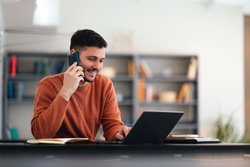 Hombre calculando la cuota mensual de su prestamo y comunicandose con Qida por teléfono